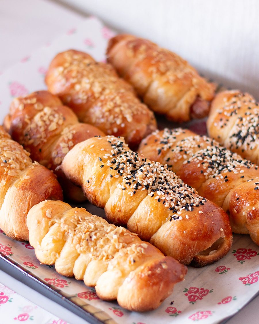 Licensed stock photograph: sausage rolls baked inside soft golden dough and topped with sesame and nigella seeds
