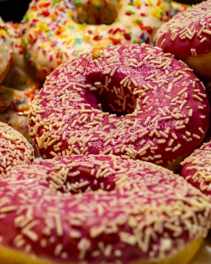 Licensed stock photograph: pink iced ring donuts under a dense layer of white sprinkles